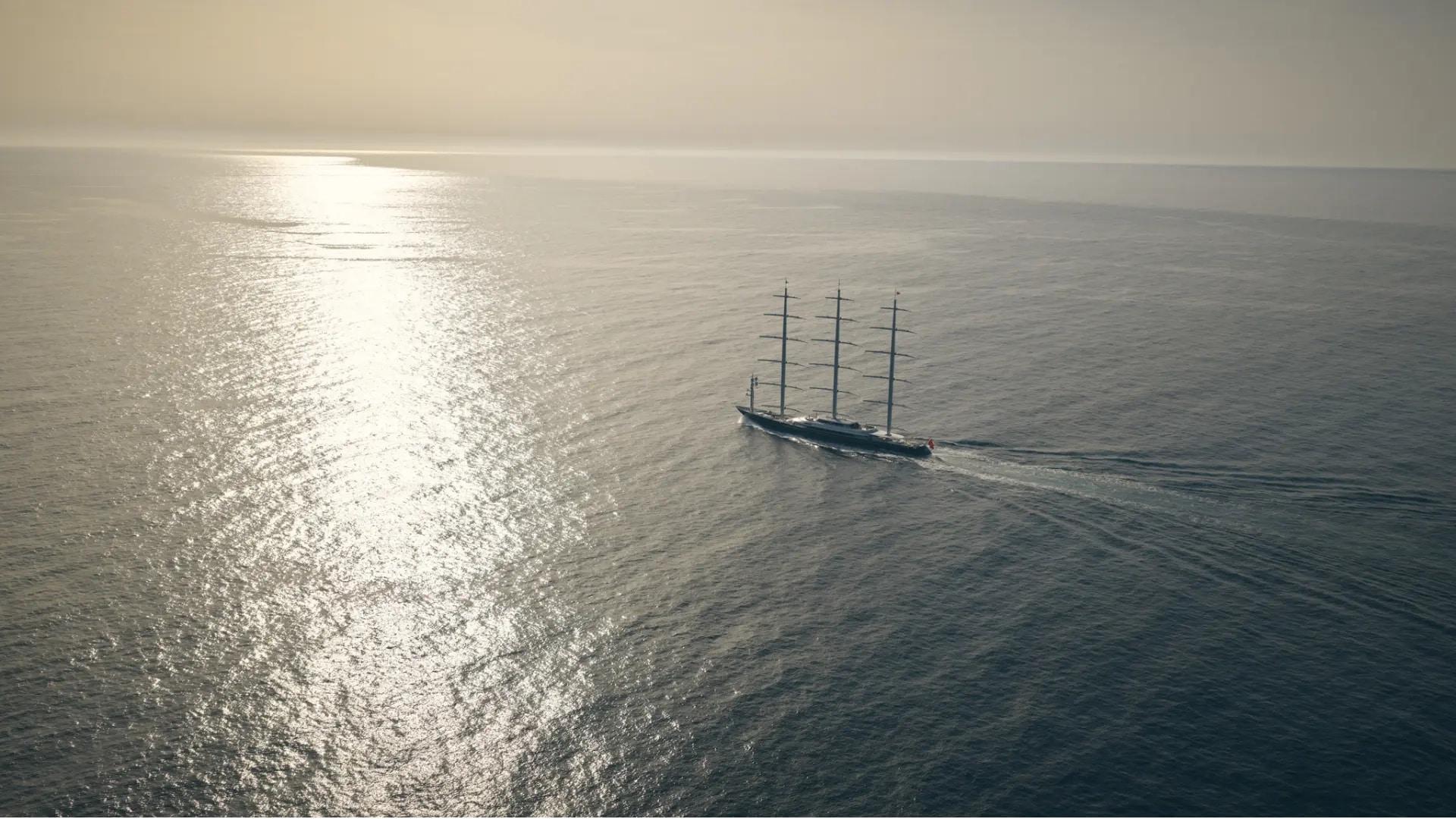A sailing yacht crossing an open sea in golden sunlight